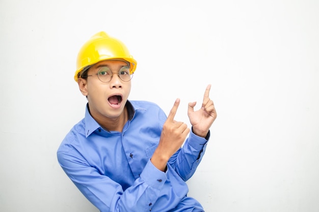 vue latérale d'un travailleur de la construction asiatique choqué heureux pointant du doigt et présentant quelque chose d'annonces.