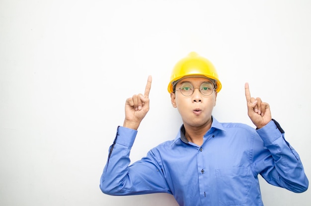 vue latérale d'un travailleur de la construction asiatique choqué heureux pointant du doigt et présentant quelque chose d'annonces.