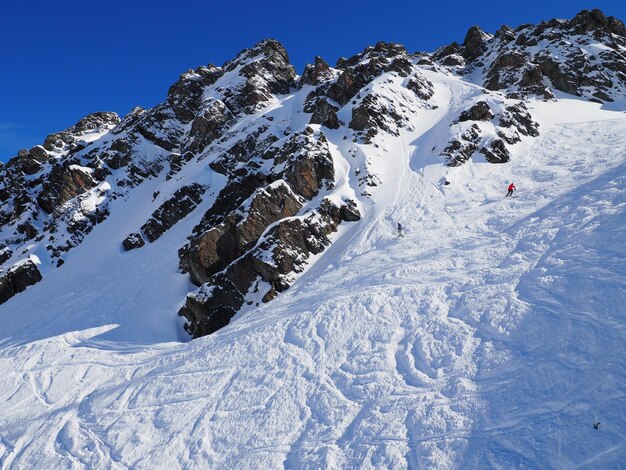 Vue lointaine d'une personne en train de skier sur une montagne rocheuse couverte de neige