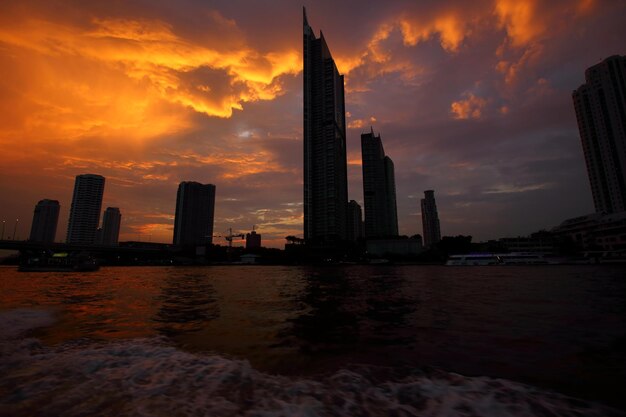 Photo vue le long de la rivière chao phraya près du pont sathon au coucher du soleil à bangkok