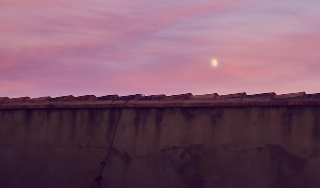 Vue sur la lune au coucher du soleil depuis les toits des immeubles de la ville