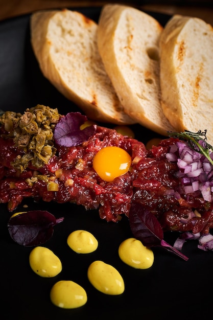 Vue macro rapprochée du tartare de boeuf avec œuf et pain au restaurant Photo de haute qualité