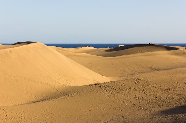 Une vue magnifique sur les dunes de sable de Maspalomas avec l'océan bleu en arrière-plan à Gran Canaria Espagne