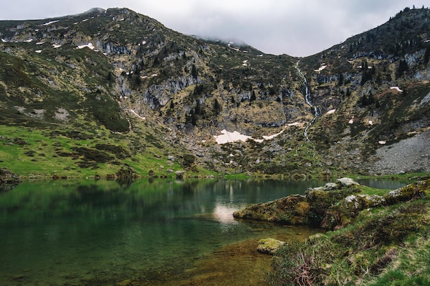 Vue sur le magnifique lac bleu des Ayes, avec une cascade, les pâturages et les sommets de France