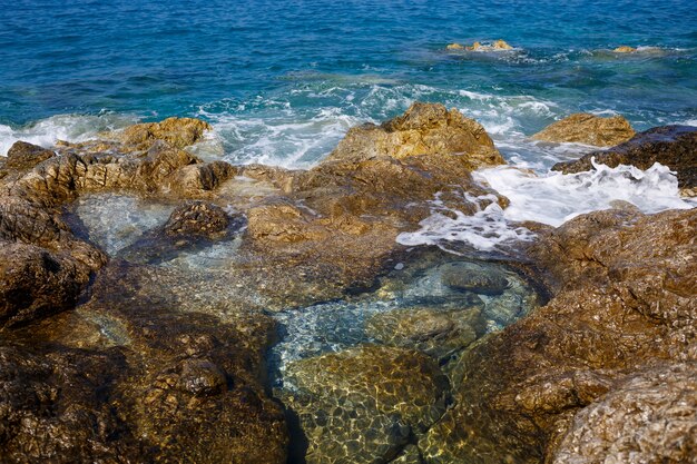 Une vue magnifique sur la mer Méditerranée bleue. Rochers ensoleillés, vagues avec mousse et éclaboussures d'eau. La vague s'écrase sur les rochers sur le rivage