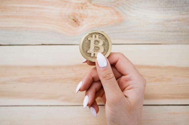 Photo une vue de la main de la femme tenant des bitcoins sur fond en bois