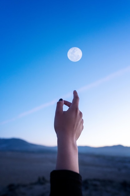 Vue de la main pointant ou touchant le ciel et la lune