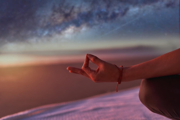 Vue de la main en position de méditation ou de yoga mudra à l'extérieur sur la plage la nuit