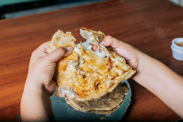 Vue des mains divisant de délicieuses pupusas salvadoriennes sur une table en bois Concept de pupusas traditionnelles faites à la main Mains divisant de délicieuses pupusas nicaraguayennes sur la table