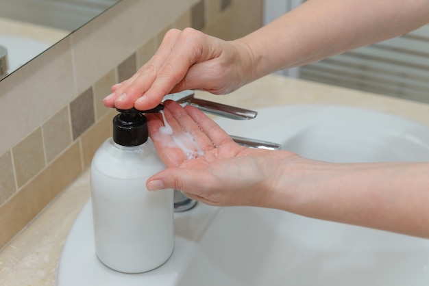 Vue des mains féminines presser du savon liquide dans la paume d'un gros plan de main