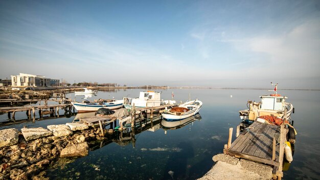 Vue sur la mer composée de bateaux de pêche reliés à d'anciennes jetées en bois dans le district d'Ezine à Çanakkale