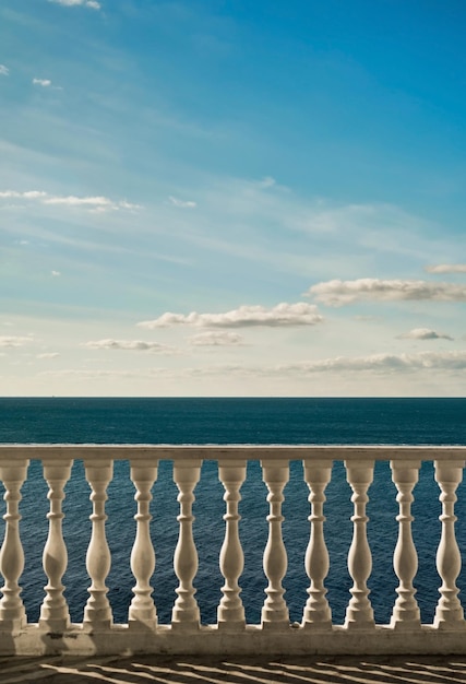 Vue sur la mer depuis le balcon contre un ciel bleu vif avec des nuages cadre vertical Vue sur la mer calme depuis la terrasse de l'hôtel