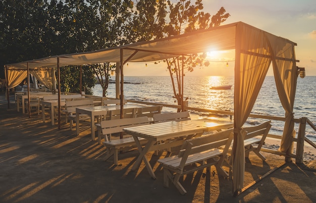 Vue mer avec table design blanche et tissu avec éclairage au lever du soleil.