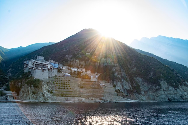 Vue d'un monastère chrétien orthodoxe à la montagne avec un coucher de soleil sur l'eau