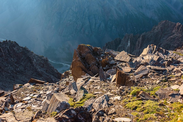 Vue sur la montagne ensoleillée depuis la falaise à très haute altitude Paysage alpin pittoresque avec de beaux rochers pointus et des couloirs au soleil Beau paysage au bord de l'abîme avec des pierres pointues et de l'herbe verte