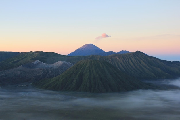 Photo vue des montagnes de bromo et semeru contre le ciel au lever du soleil sa savane est couverte par la brume