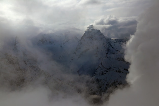 Vue sur les montagnes enneigées du Caucase à travers les nuages