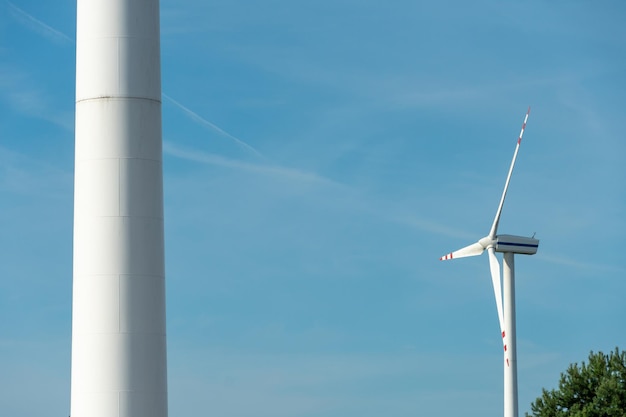 Vue d'un moulin à vent moderne contre un ciel bleu Les pales blanches de l'éolienne se bouchent Source d'énergie renouvelable Production d'électricité bon marché et sûre