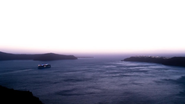 Vue nocturne d'un bateau de croisière quittant Santorin après le coucher du soleil