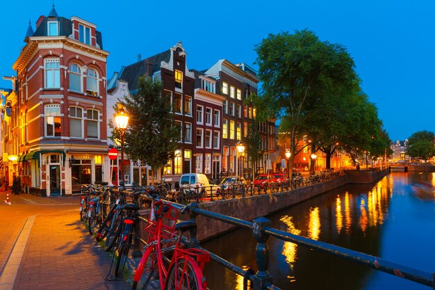 Vue nocturne sur la ville d'Amsterdam canal, pont avec maisons typiques et vélos, Hollande, Pays-Bas.