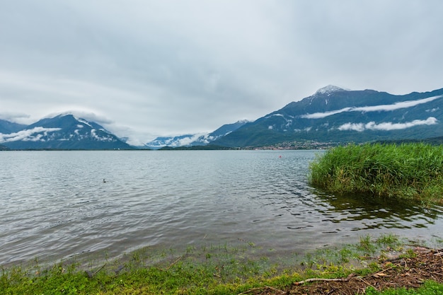 Vue nuageuse d'été sur le lac de Côme (Italie) avec de la neige au sommet du mont