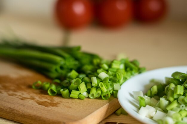 La vue de l'oignon vert et du tas de tomates sur la planche à découper en bois