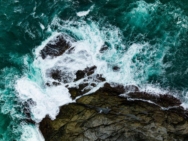 Vue d'oiseau sur le rivage avec de grandes vagues s'écrasant sur la falaise de roche Belles vagues à la surface de la mer dans un jour ensoleillé d'été Arrière-plan magnifique paysage marin vue de dessus vue sur le paysage côtier