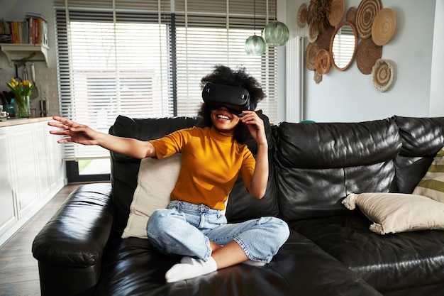 Photo vue panoramique d'une adolescente portant un simulateur de réalité virtuelle pour jouer à un jeu vidéo dans le salon
