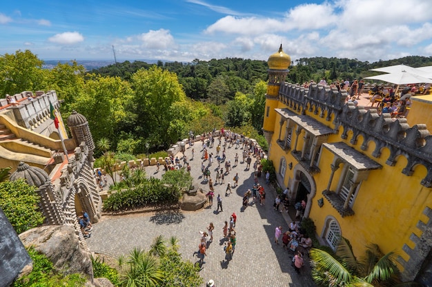 Vue panoramique aérienne des touristes visitant le palais de Pena et la terrasse du restaurant pleine de gens qui prennent des collations et contemplent les montagnes verdoyantes de Sintra