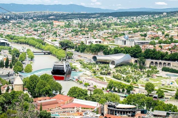 Vue panoramique aérienne de la vieille ville historique de Géorgie Tbilissi avec une machine de téléphérique en gros plan par une journée ensoleillée avec le pont de la rivière PeaceRike, le parc, la mosquée et les toits des bâtiments d'architecture