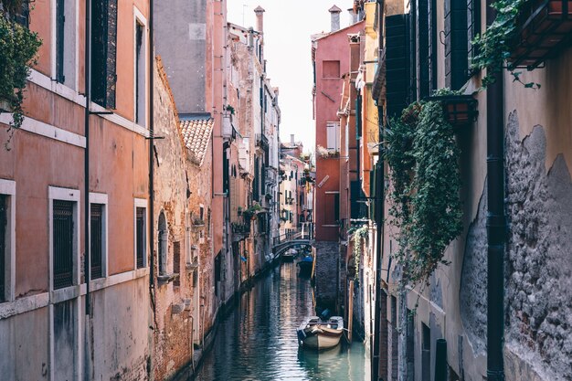 Vue panoramique sur le canal étroit de Venise avec des bâtiments historiques et un bateau depuis le pont. Paysage de journée ensoleillée d'été