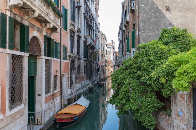 Vue panoramique sur le canal étroit de Venise avec des bâtiments historiques et un bateau depuis le pont. Paysage de journée ensoleillée d'été