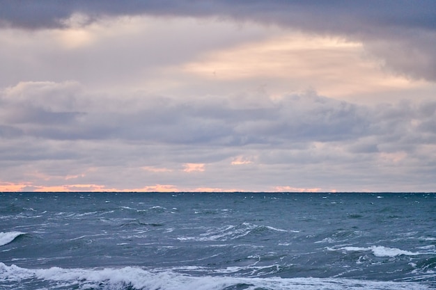 Vue panoramique sur le ciel nuageux violet et la mer bleue avec des vagues écumantes. Temps venteux, beau paysage de la mer Baltique en soirée.