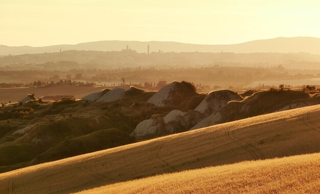 Photo vue panoramique des collines et des montagnes d'argile de la toscane dans la lumière dorée des tours de sienne en arrière-plan
