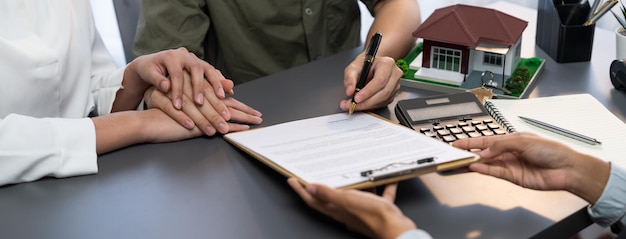 Vue panoramique d'un couple marié signant un contrat de prêt immobilier avec le courtier Prodigy