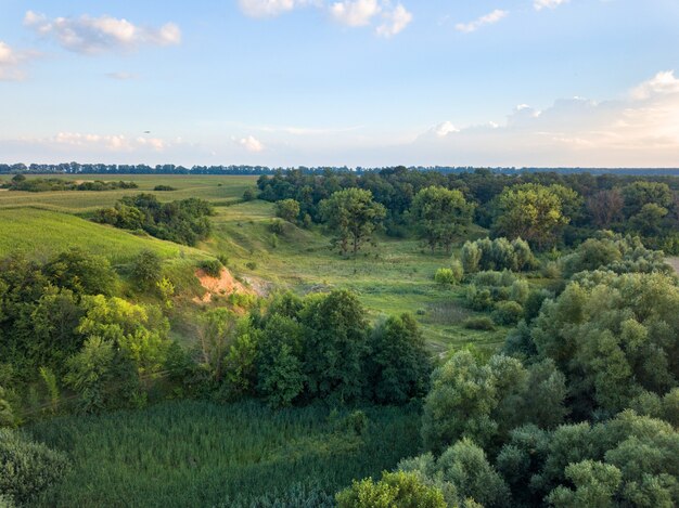 Vue panoramique depuis le drone d'un paysage naturel avec verdure, forêt, champ, ravin dans le contexte d'un ciel bleu nuageux au coucher du soleil dans la journée d'été.