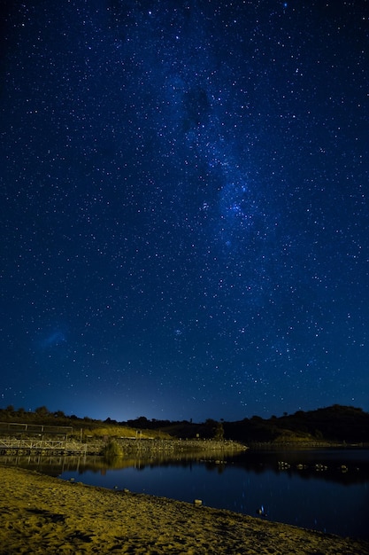 Vue panoramique du lac contre le champ d'étoiles bleues la nuit