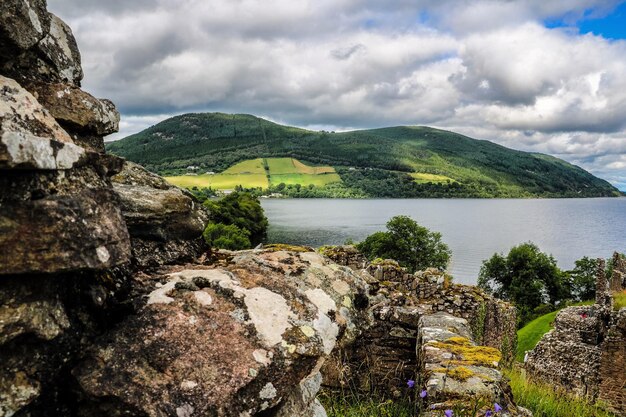Vue panoramique du lac entouré de montagnes contre un ciel nuageux