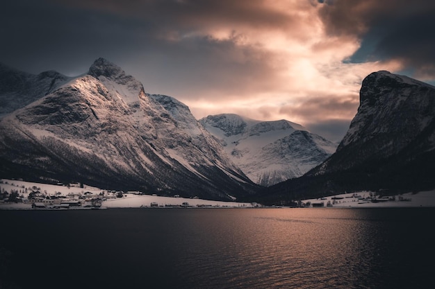 Vue panoramique du lac par les montagnes enneigées contre le ciel au coucher du soleil