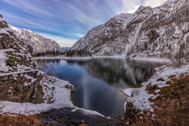 Vue panoramique du lac par les montagnes enneigées contre le ciel