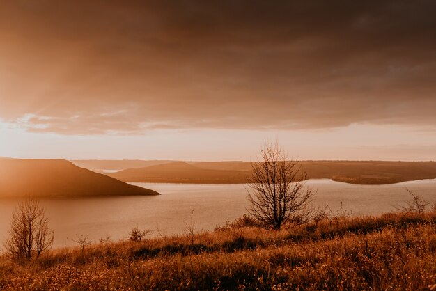 Vue panoramique de la falaise à la grande rivière lac mer au loin silhouettes des îles, coucher de soleil coucher de soleil orange fougueux