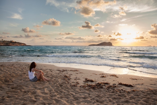 Vue panoramique d'une femme sur une plage au coucher du soleil à Ibiza