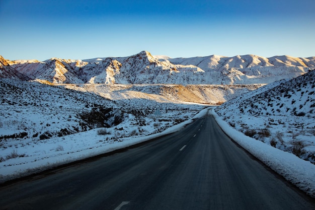 Vue panoramique d'hiver depuis la route goudronnée dans les montagnes couvertes de neige sur un fond