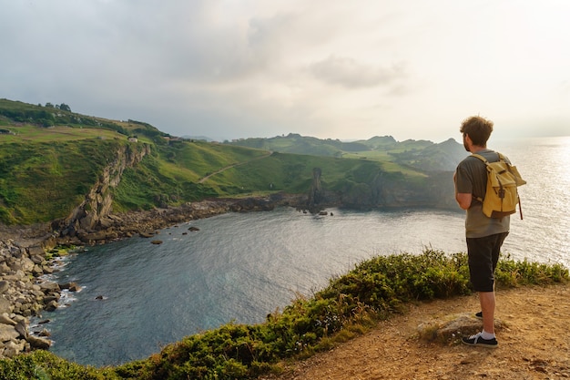 Vue panoramique d'un homme méconnaissable assis dans une falaise. Vue horizontale du routard voyageant en plein air