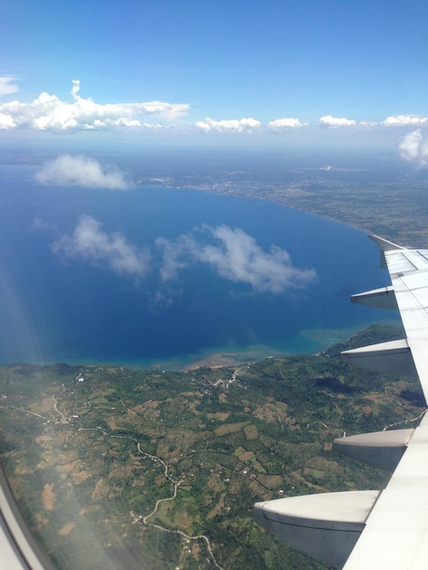 Vue panoramique de la mer et de l'aile de l'avion vue à travers une fenêtre en verre