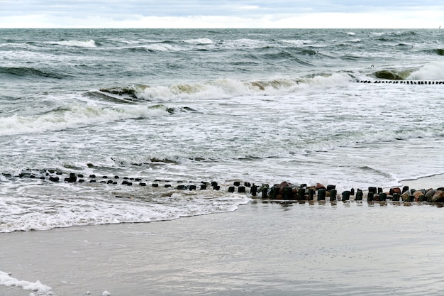 Vue panoramique sur la mer bleue avec des vagues bouillonnantes et écumantes. Vintage longs brise-lames en bois s'étendant loin vers la mer, paysage d'hiver de la mer Baltique. Silence, solitude, calme et paix.