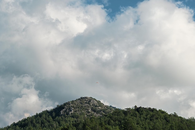 Vue panoramique sur la montagne avec des parapentes volant à haute altitude et des nuages blancs moelleux photo panoramique des montagnes à midi sur la côte égéenne