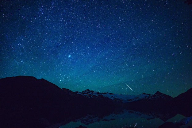 Vue panoramique des montagnes enneigées contre le champ d'étoiles la nuit