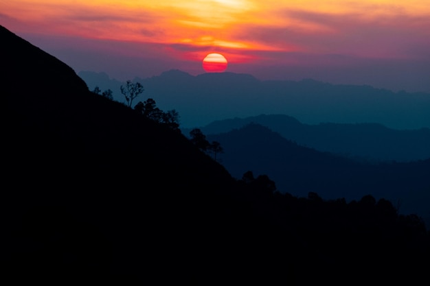 Photo vue panoramique sur les montagnes silhouette contre le ciel pendant le coucher du soleil et le faisceau