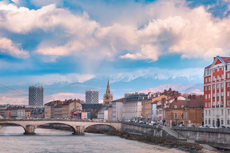 Photo vue panoramique sur les rives de l'isère et le pont, la collégiale saint-andré avec les alpes françaises en arrière-plan, grenoble, france